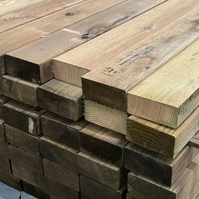 Tábuas de pinho tratado empilhadas em armazém, com veios visíveis e cortes transversais destacados nas extremidades.